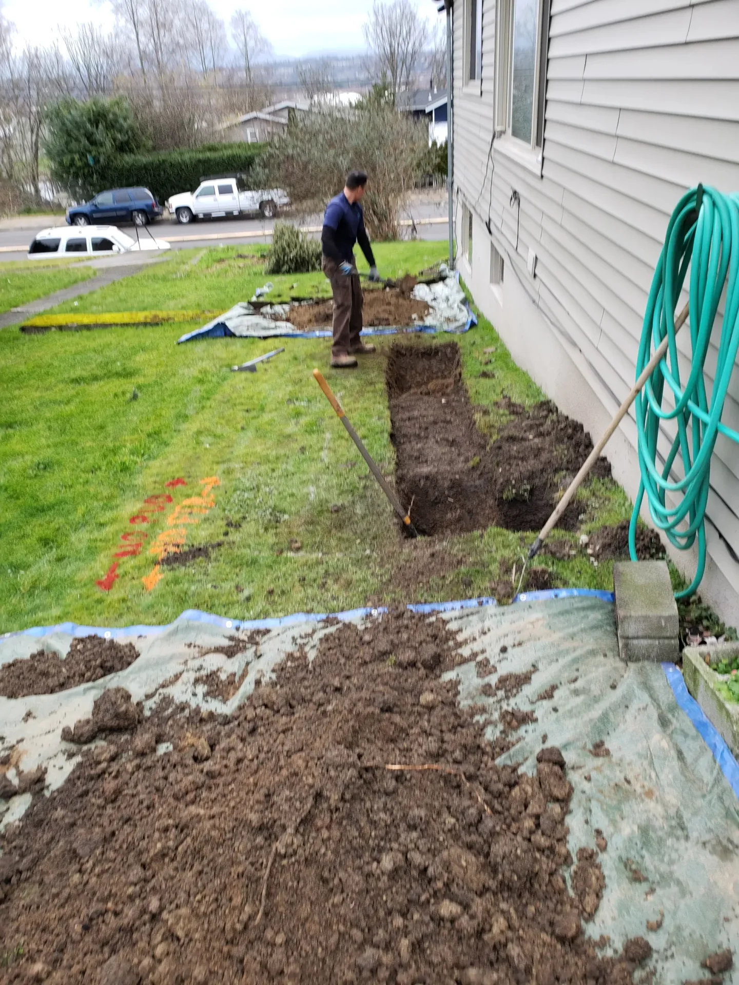 Excavation beside a house for an underground water line.