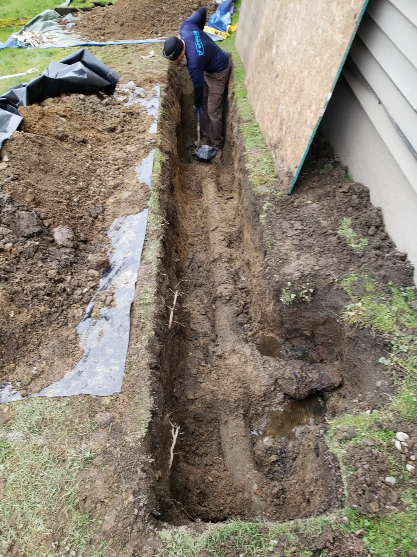 Pipe excavation beside a residential foundation.
