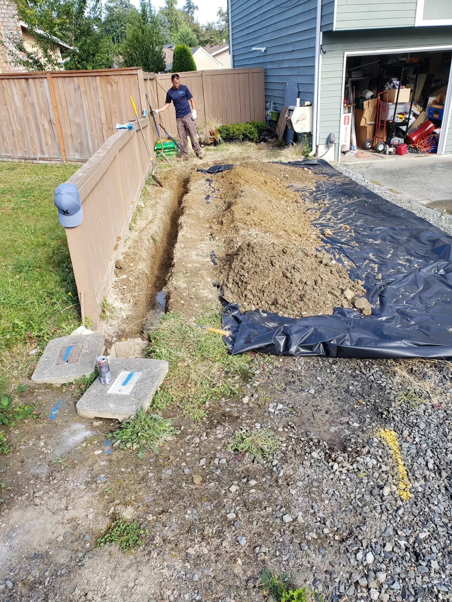 Long trench for underground pipe work beside a home.