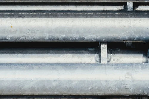 Metal pipes stacked in a horizontal arrangement, varying in size and texture.