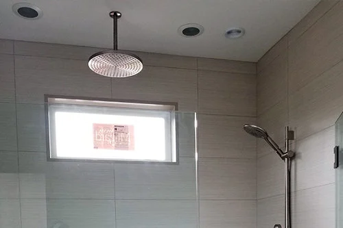 Modern shower with overhead rainfall showerhead and glass enclosure.